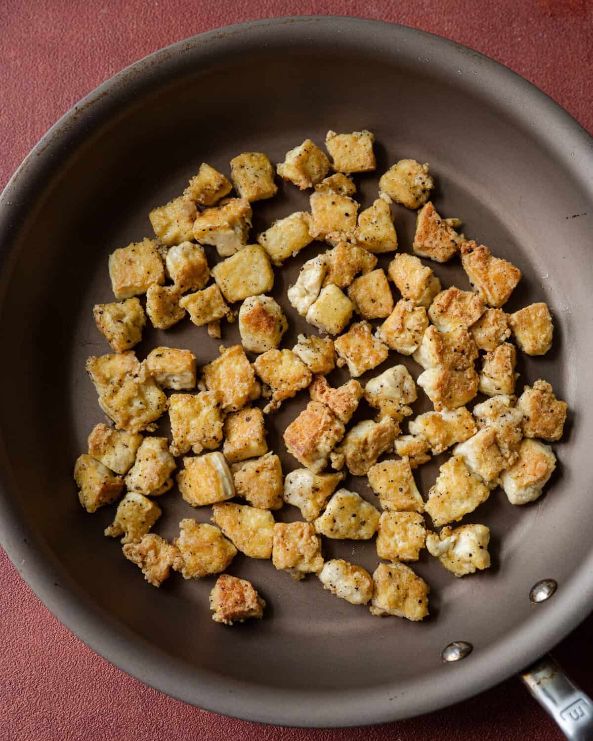 torn crispy tofu chunks in a saucepan.