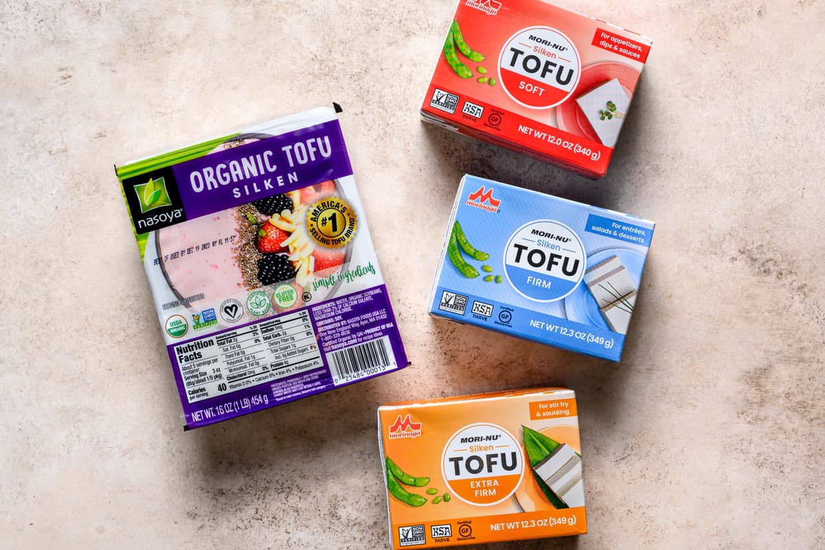 four different silken tofu varieties in packages on a table.