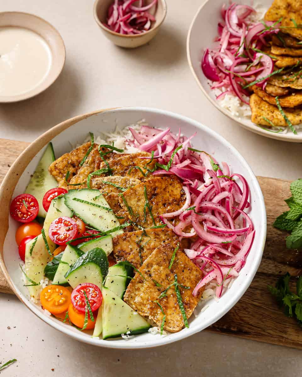 bowl of rice, pickled onions, cucumbers tomato and tofu shawarma.