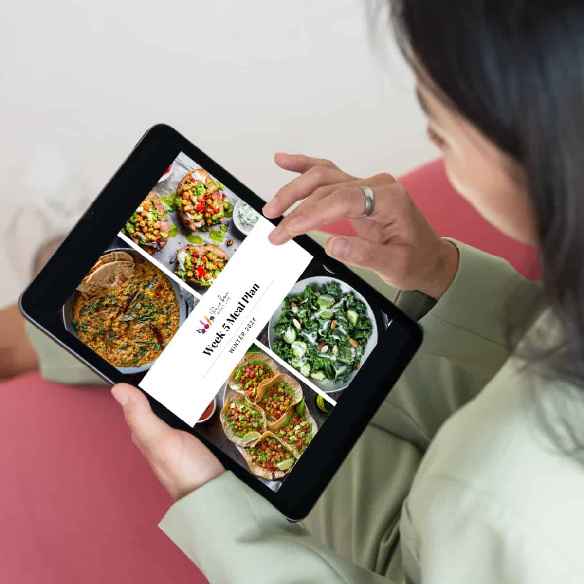 woman looking at meal plans on ipad while sitting down.
