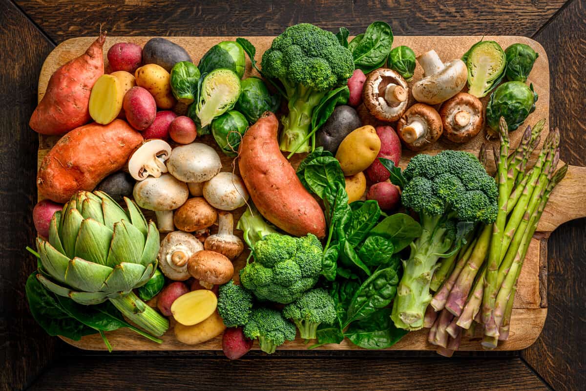 various vegetables on a large wooden cutting board.