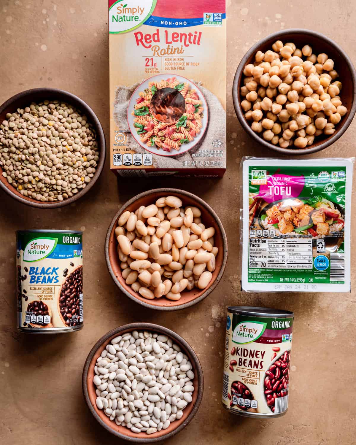 various plant proteins in bowls or in their packages on a table.