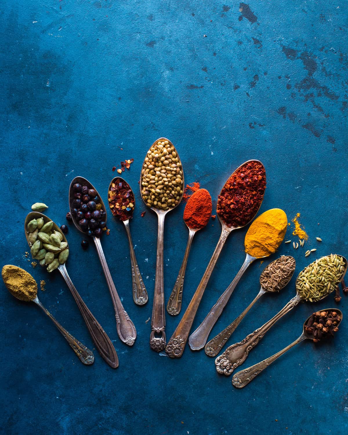 various spices in spoons on a table.