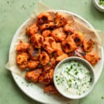 far up view of plate of buffalo cauliflower with bowl of ranch on a table.