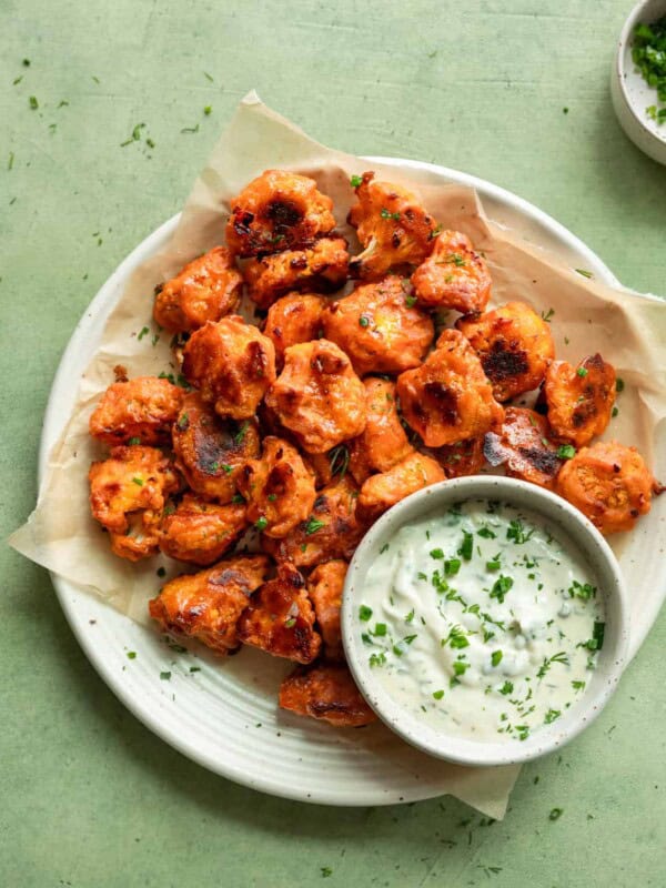far up view of plate of buffalo cauliflower with bowl of ranch on a table.