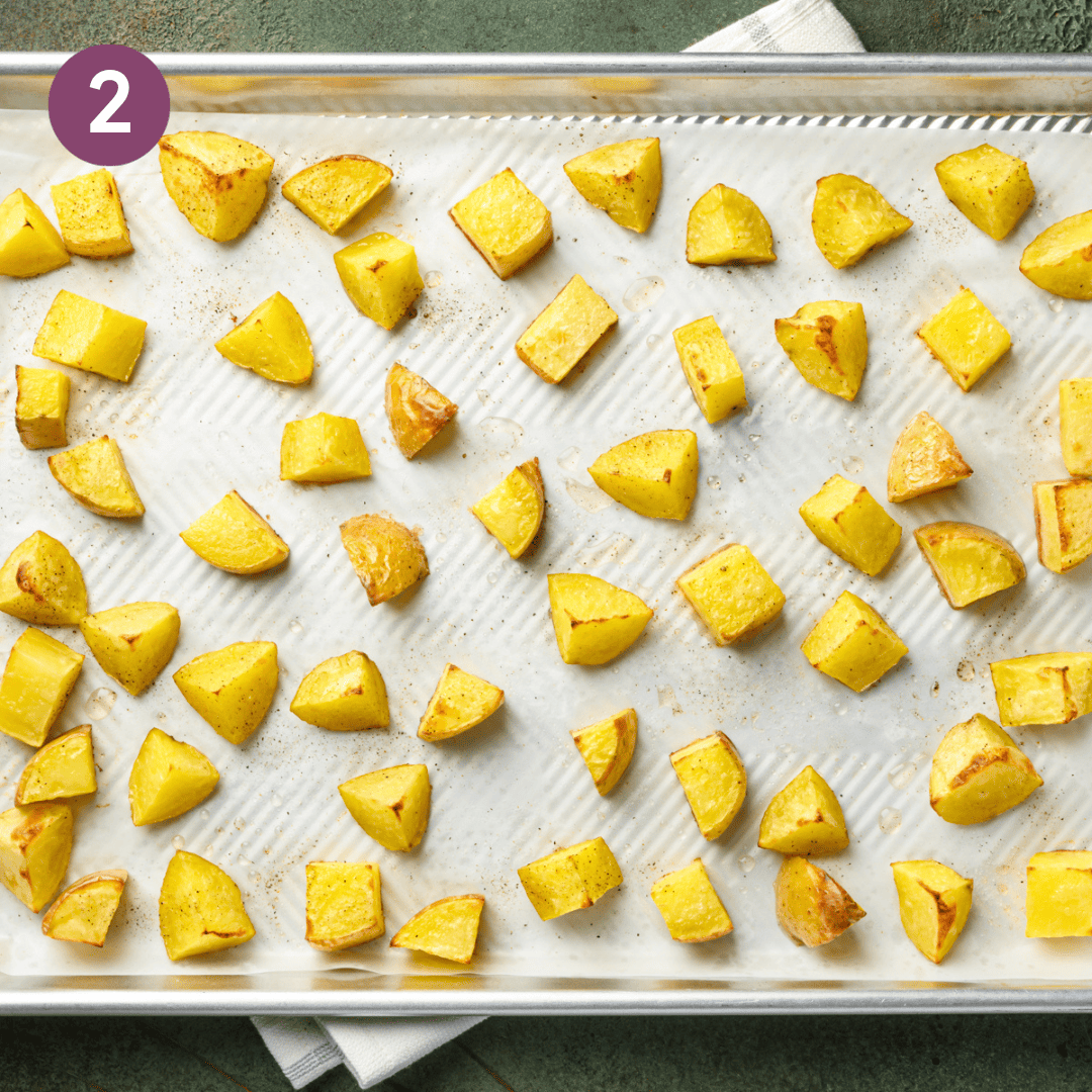 cooked cubed potatoes on a lined baking tray.