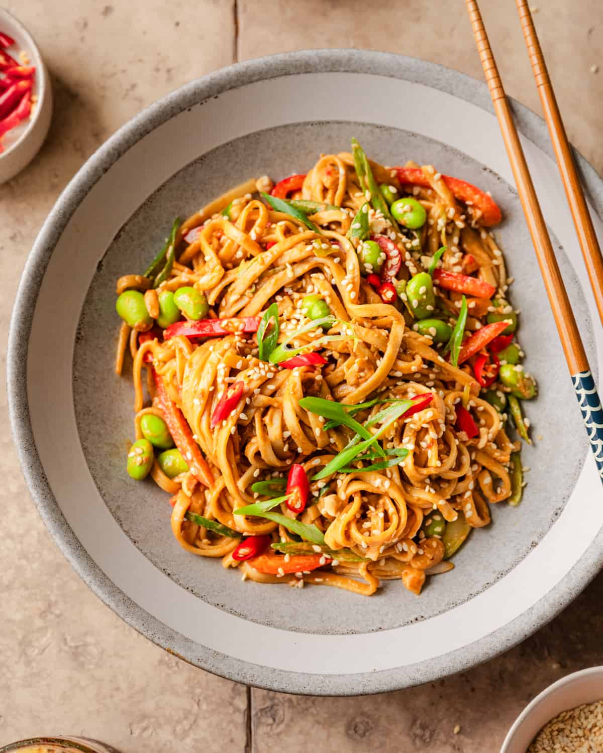 sesame noodles and chopsticks in a bowl on a table.