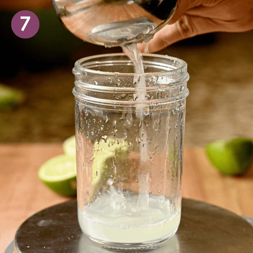 person adding lime juice to glass jar.