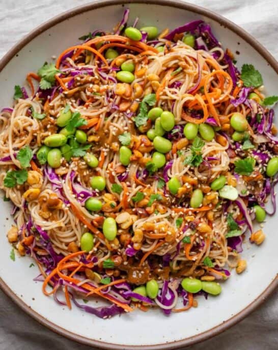 overhead view of a colorful veggie noodle salad with edamame in a bowl.