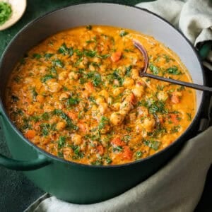 Chickpea soup with carrots and dill in a green Dutch oven with soup ladle in pot.