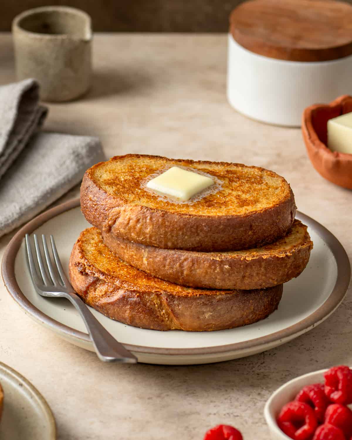 Side view of stack of french toast with a pat of butter.