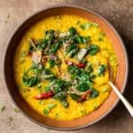 Dal palak in maroon bowl on a table.