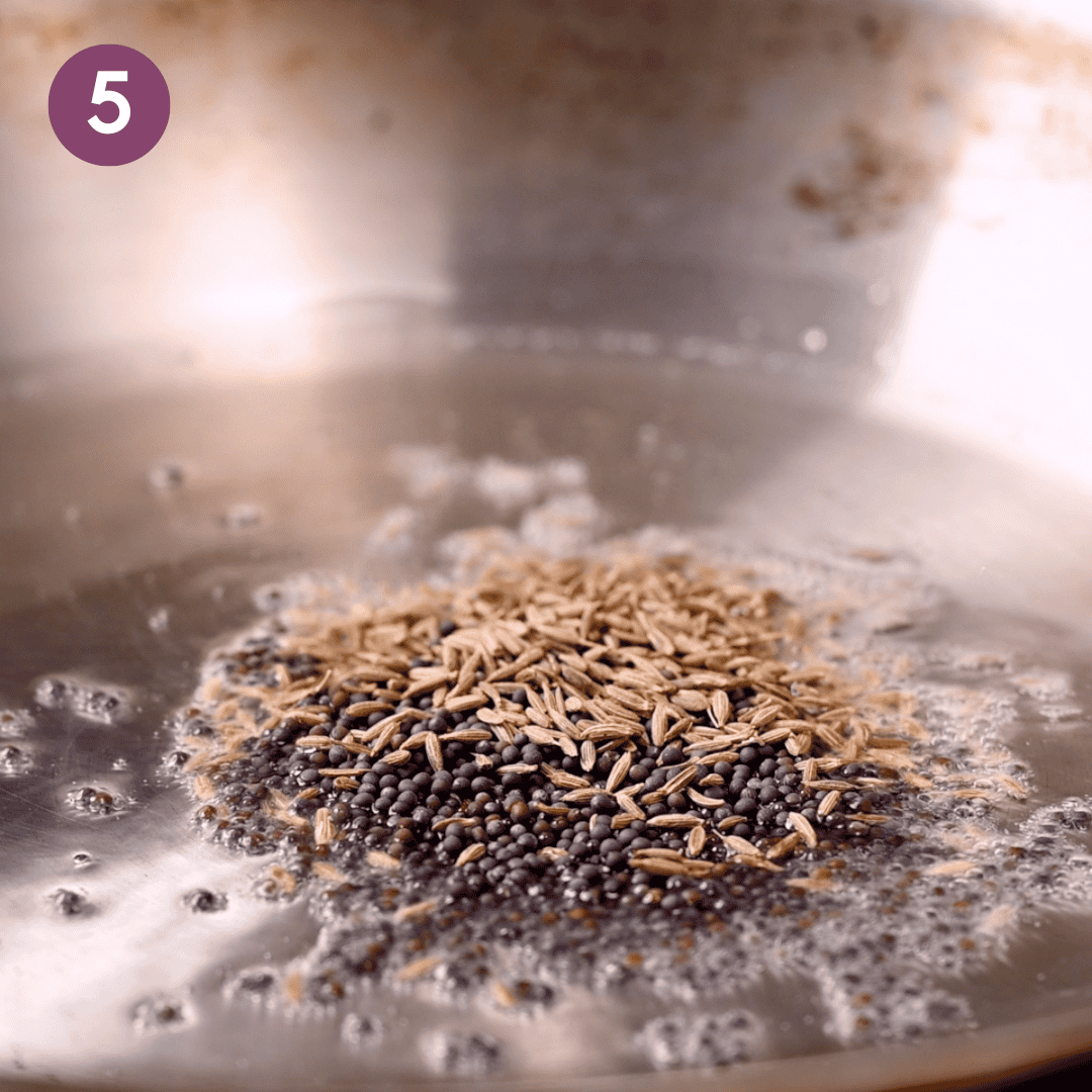 cumin and mustard seeds cooking in the oil on a saucepan.