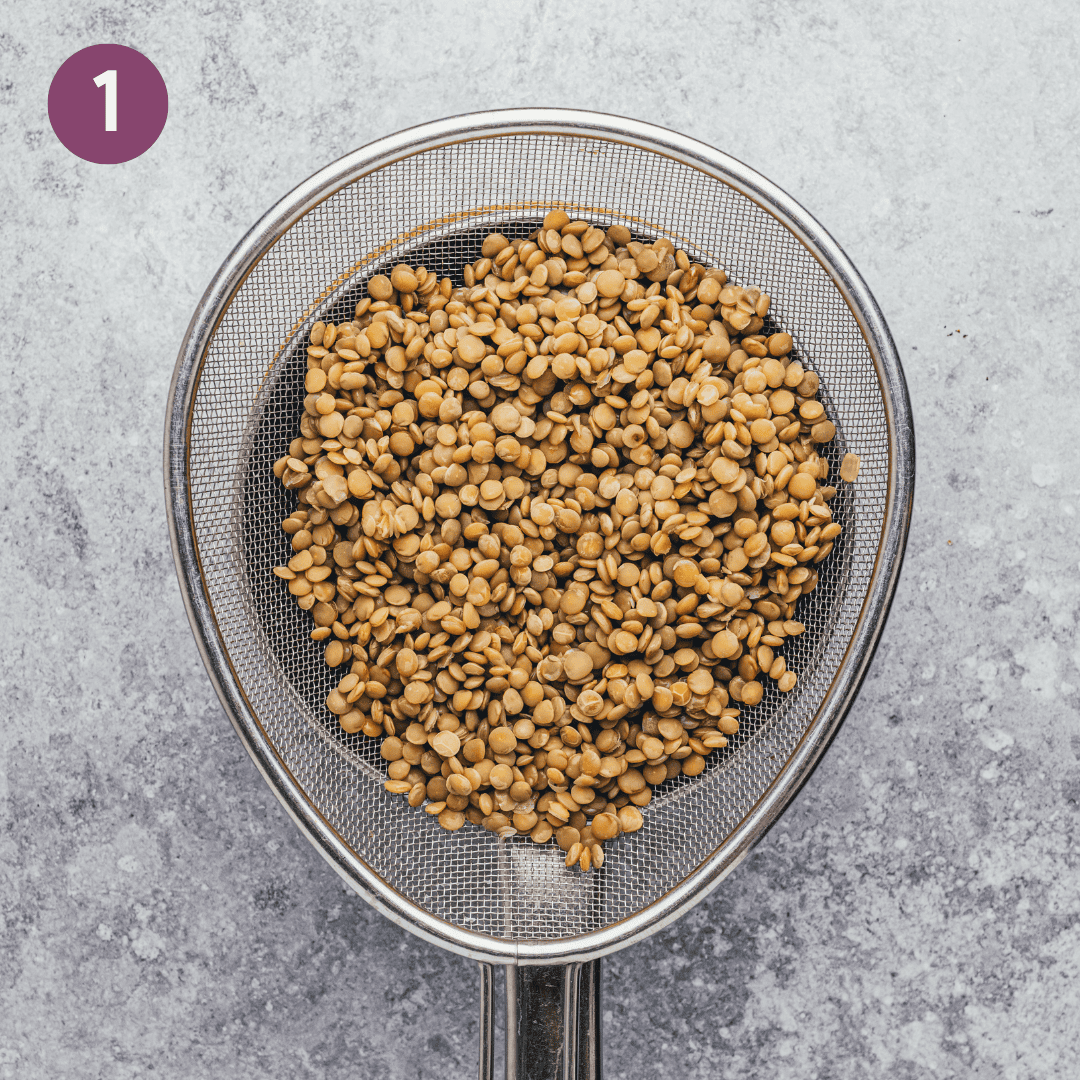 cooked green lentils drained into a metal sieve.