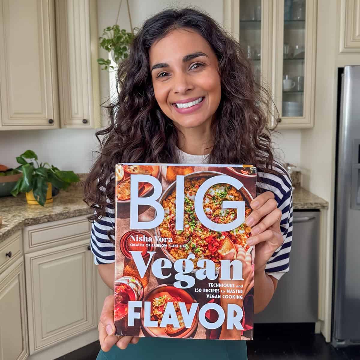 nisha holding a copy of her cookbook