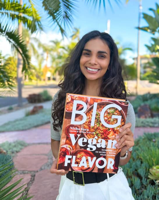 Nisha holding a copy of Big Vegan Flavor outside