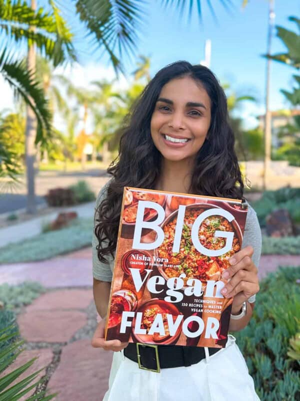 Nisha holding a copy of Big Vegan Flavor outside