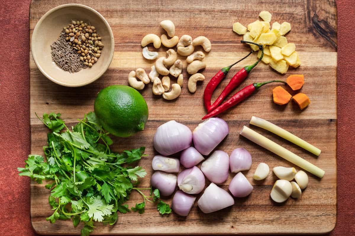 Ingredients for Malaysian laksa paste laid out on a wooden cutting board.