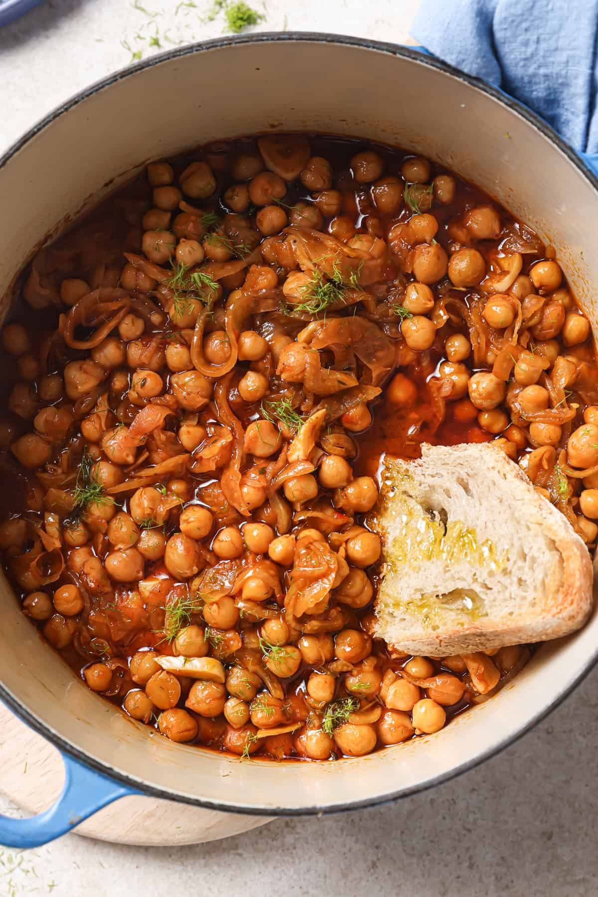 Large pot of braised chickpeas with a chunk of crusty bread.