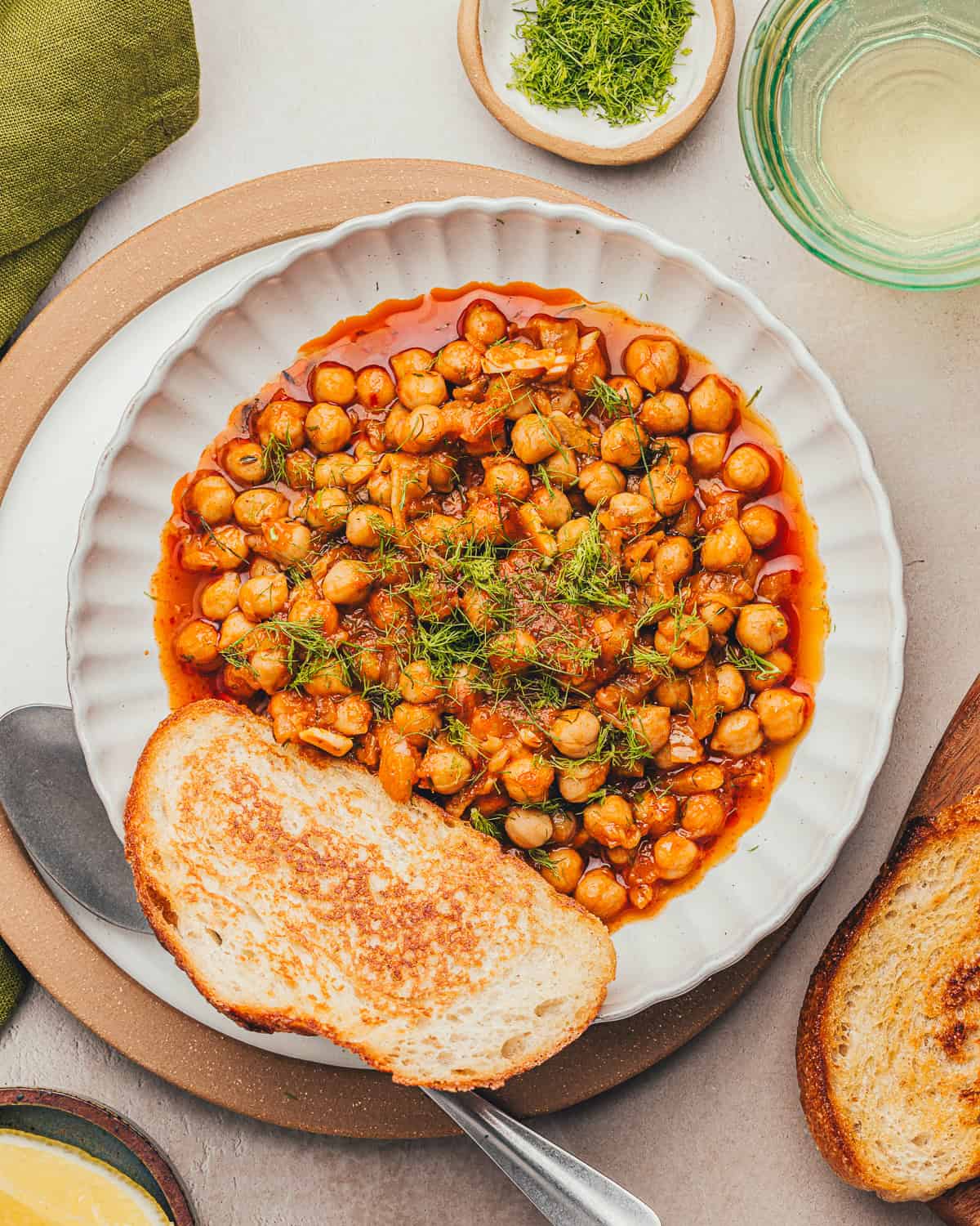 Overhead shot of bowl of braised chickpeas with a slice of bread.