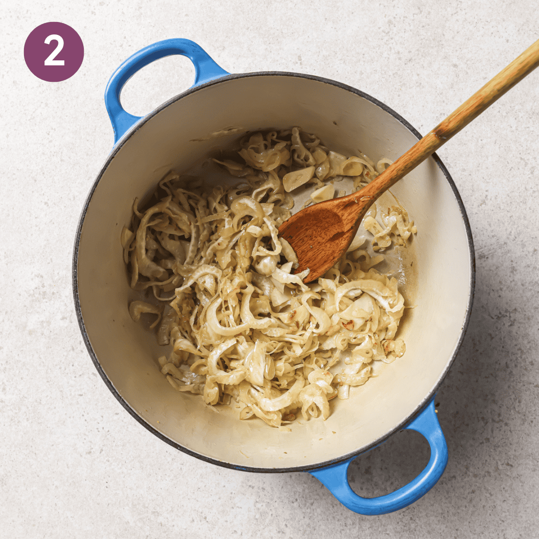 Fennel, shallot and garlic in a large pot with a wooden spoon after being cooked.