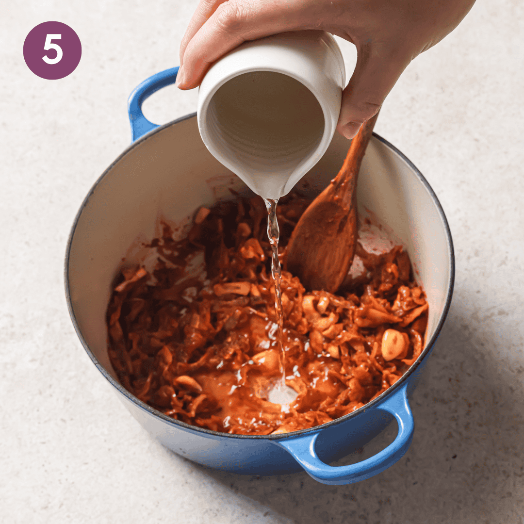 person pouring wine into the pot to deglaze it.