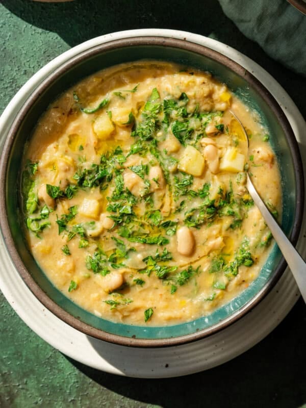 Single bowl of potato leek soup with a spoon on table.