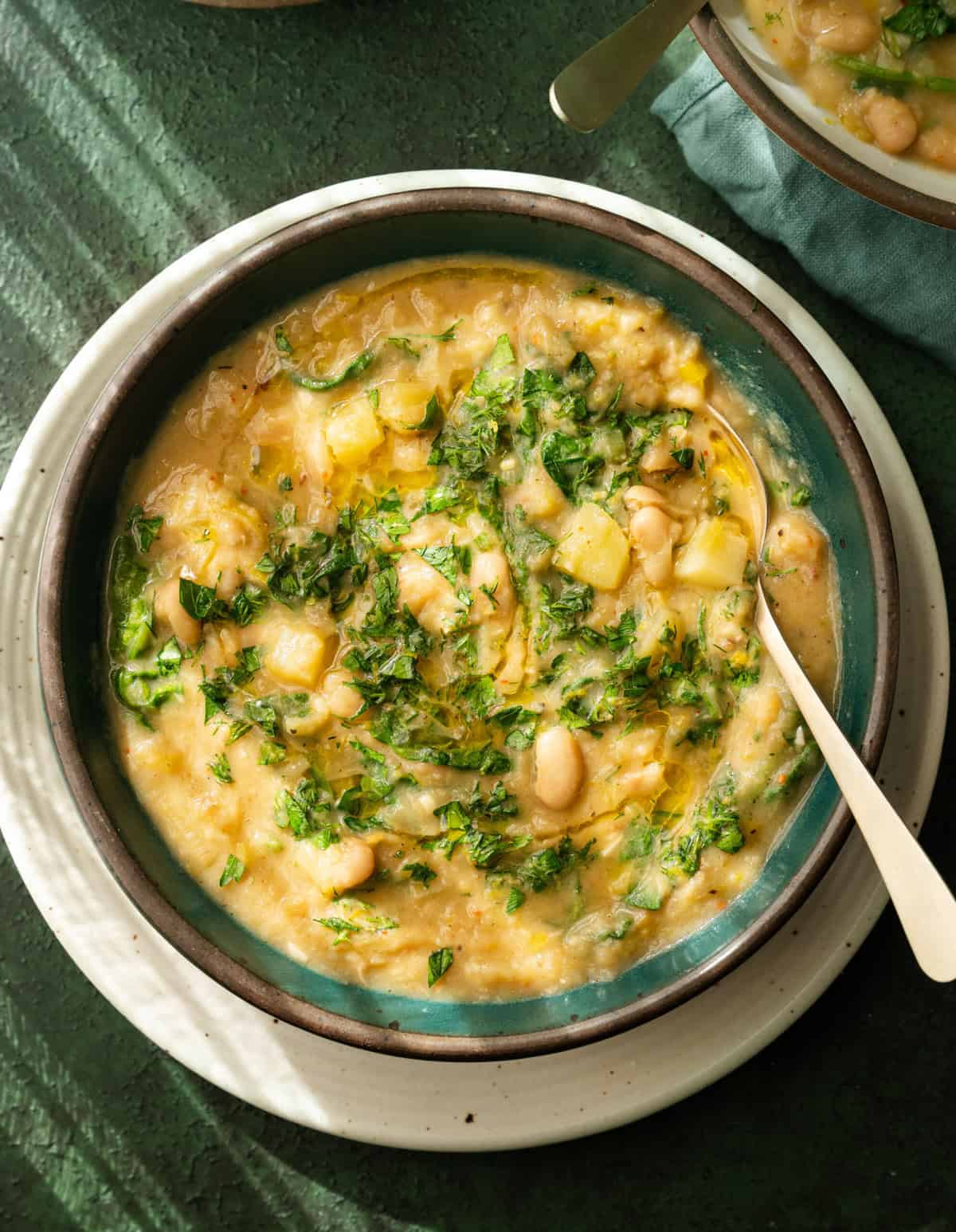 Spoon in a bowl of potato leek soup on table.