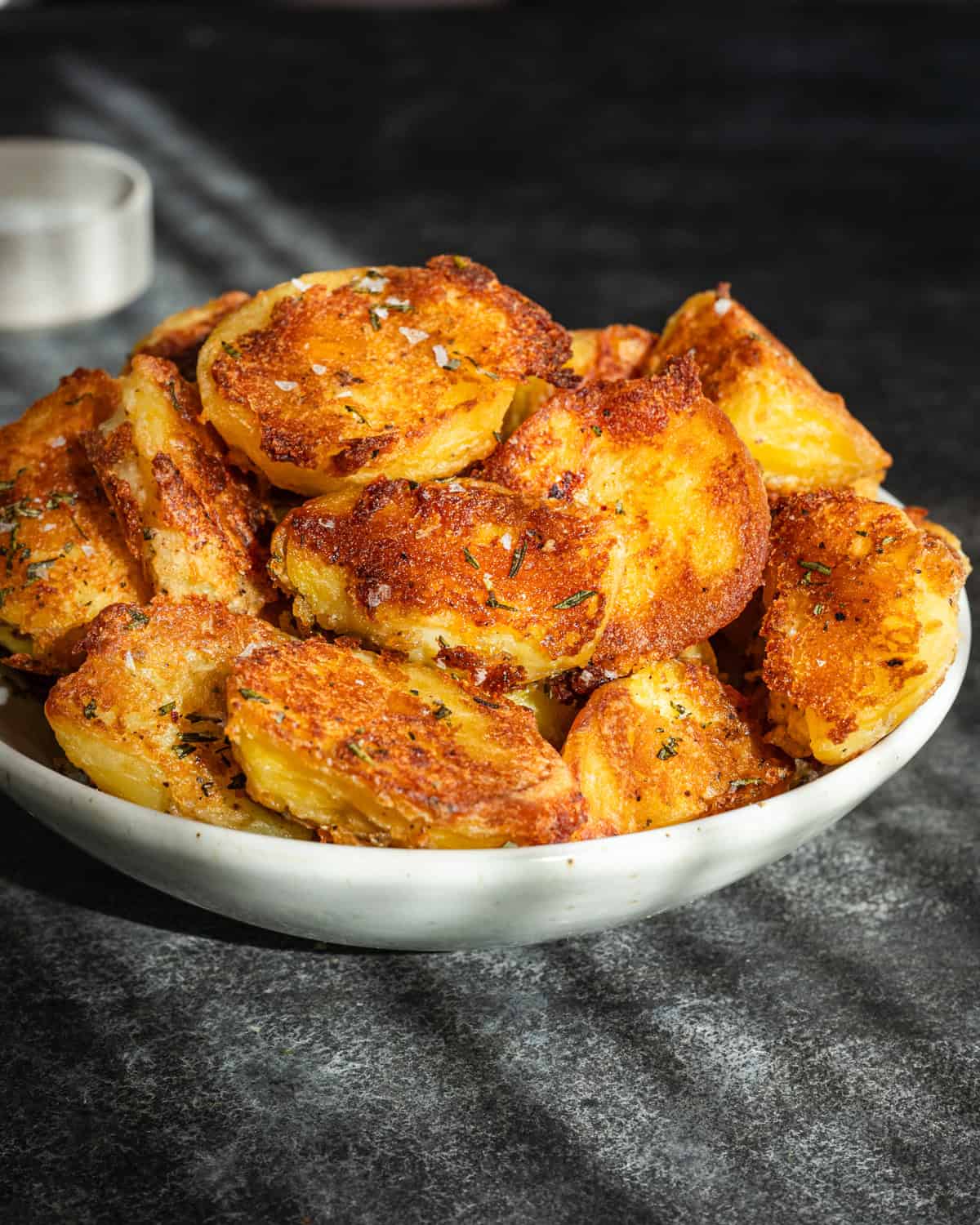 Crispy roasted potatoes in a large bowl on stone table.