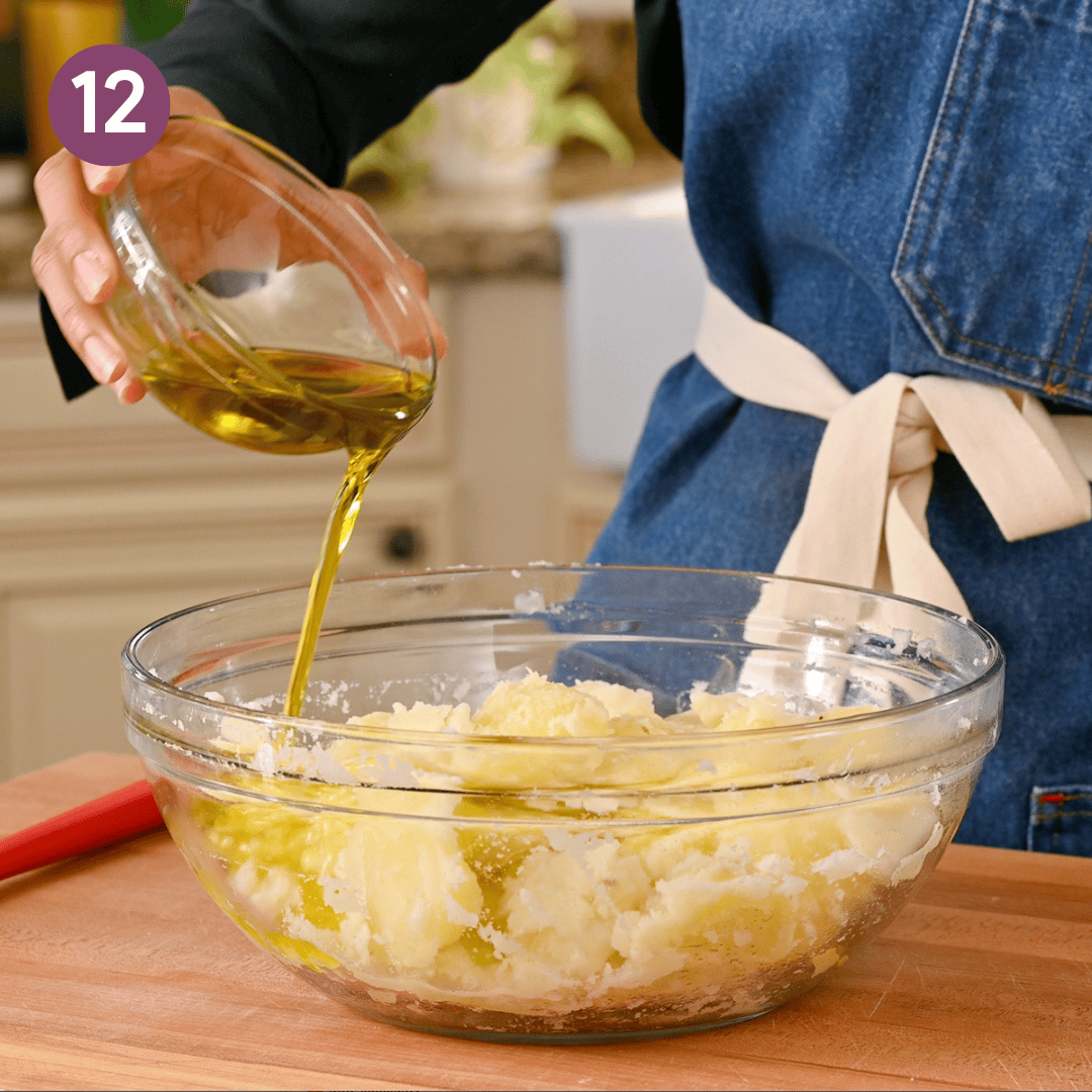 person pouring oil over potatoes.