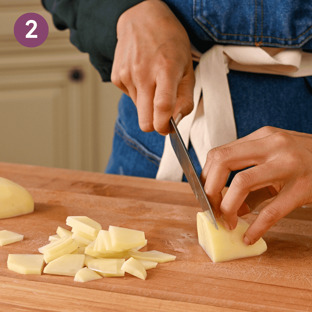 person slicing the potatoes into 1 1/2" inch pieces.