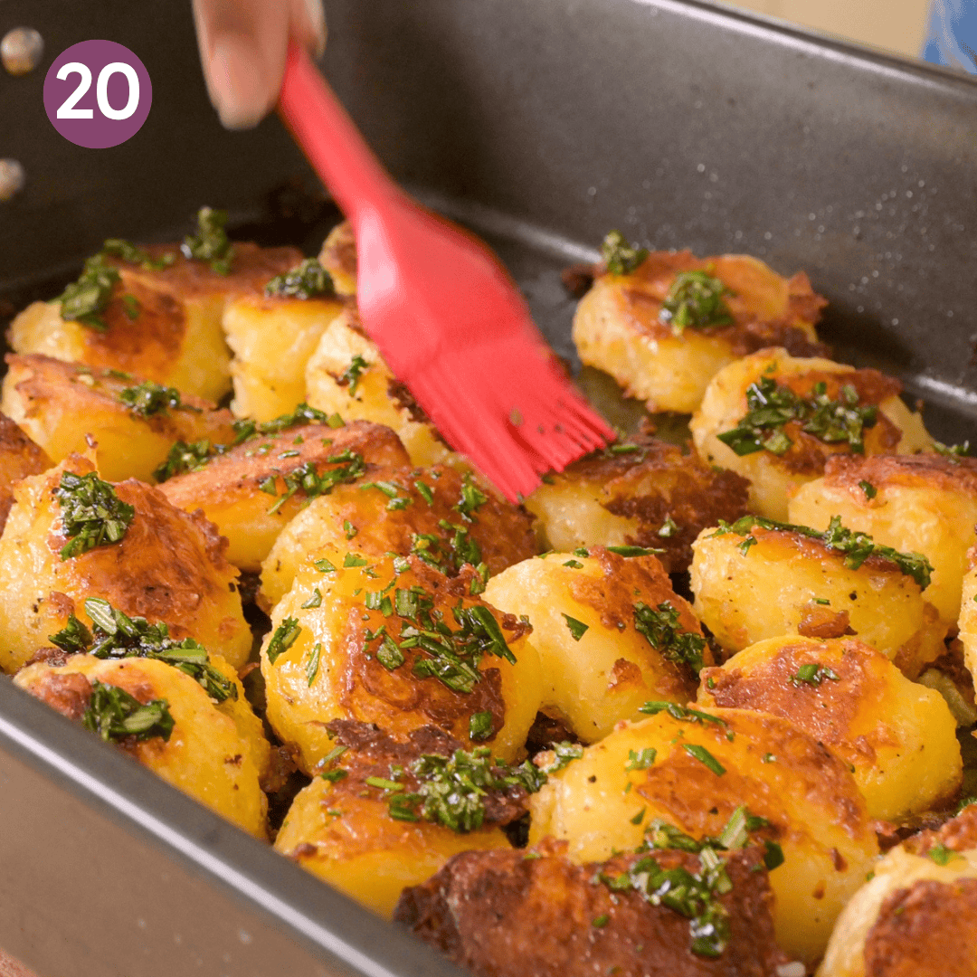 person brushing the rosemary oil over the potatoes.