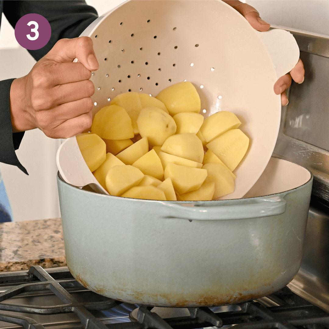 person transferring yukon gold potatoes from a colander into a pot.