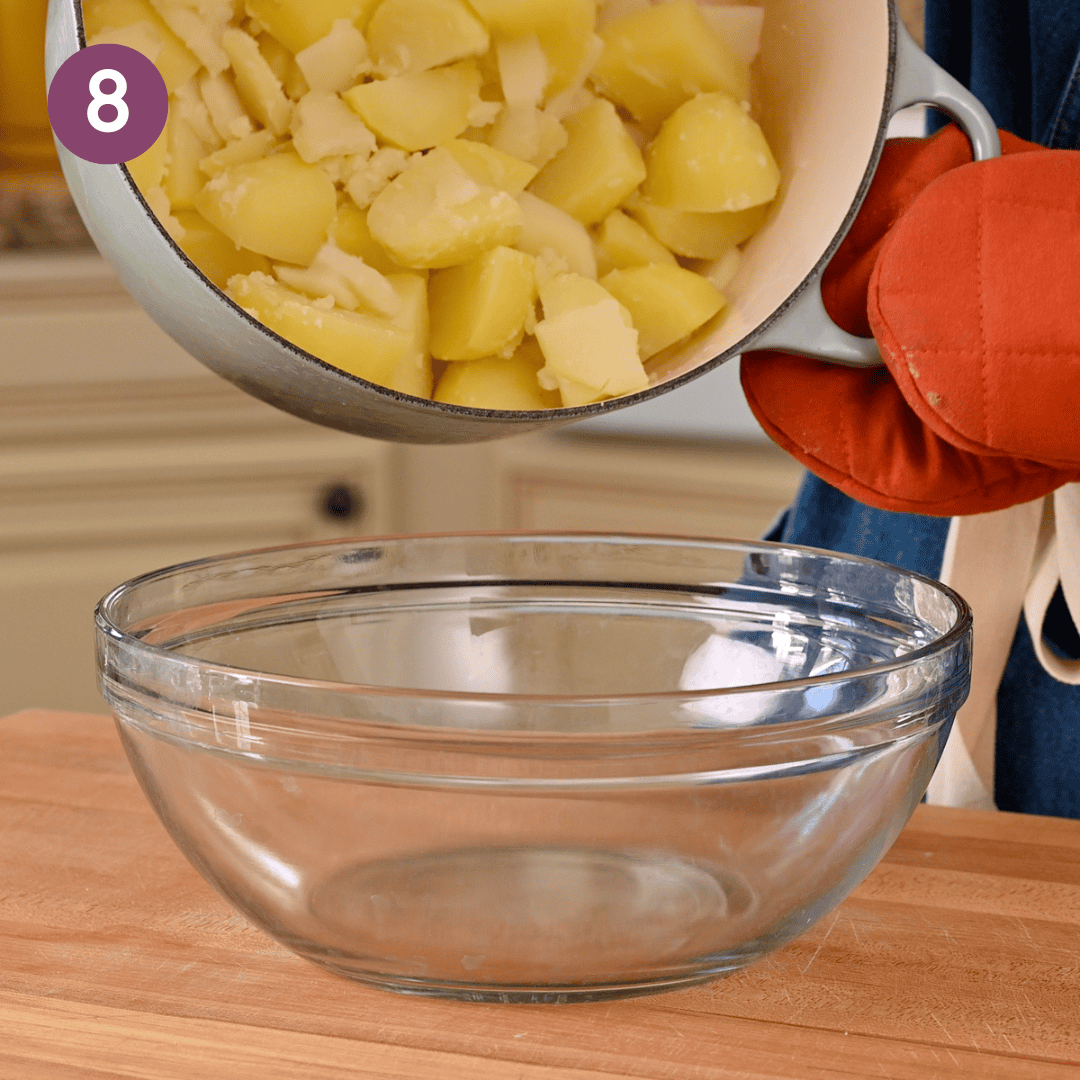 person dumping potatoes into a large bowl.