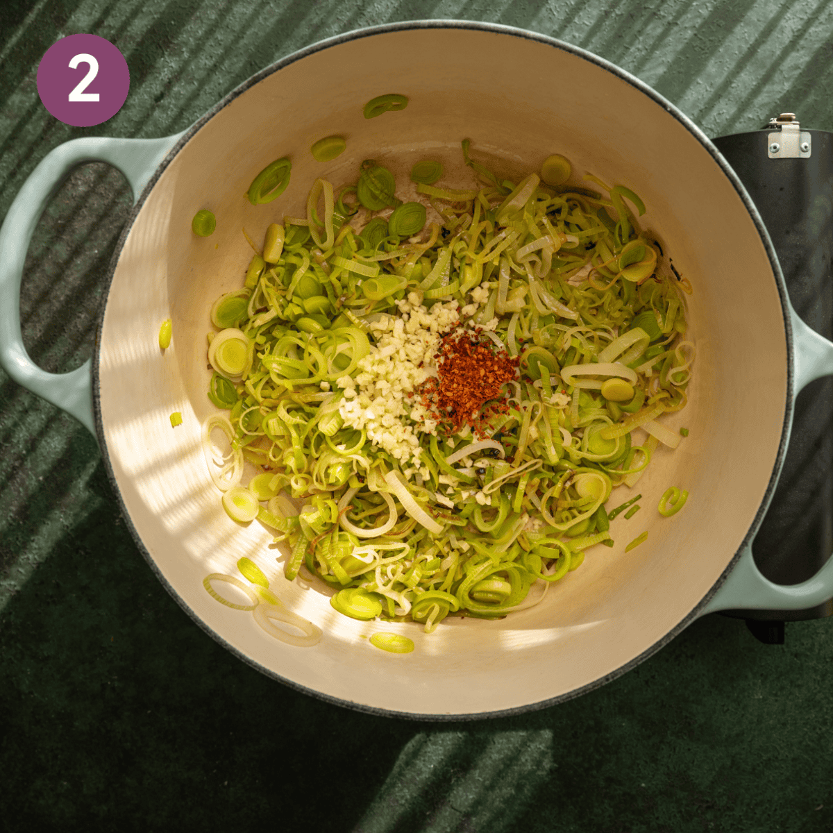 Garlic and chili flakes added to cooked leeks in dutch oven.