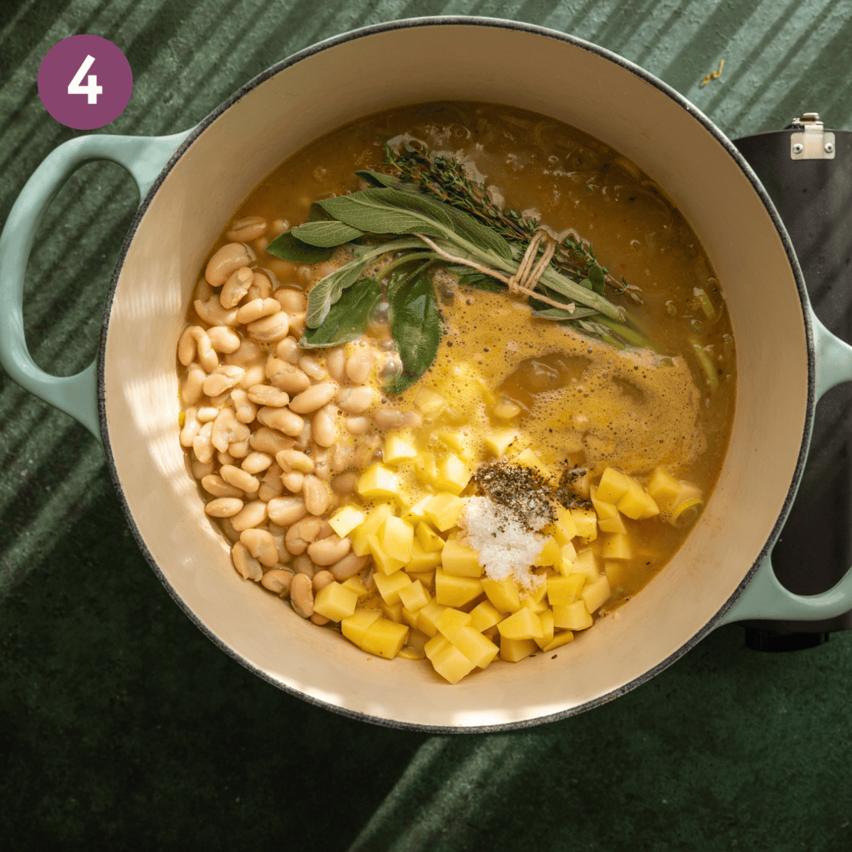 Potatoes, beans, bouquet garni, salt and pepper added to dutch oven.