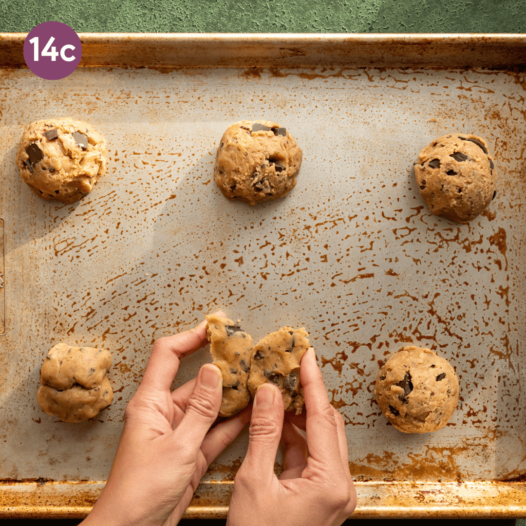 woman's hands shaping cookie dough round on a sheet pan. 