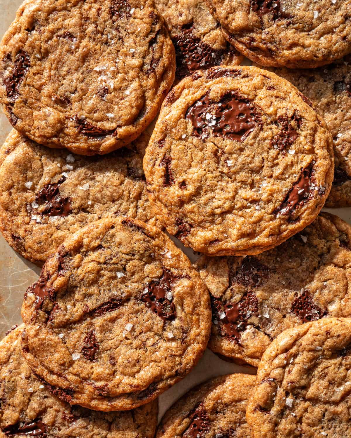 a pile of baked chocolate chip cookies on a baking sheet.