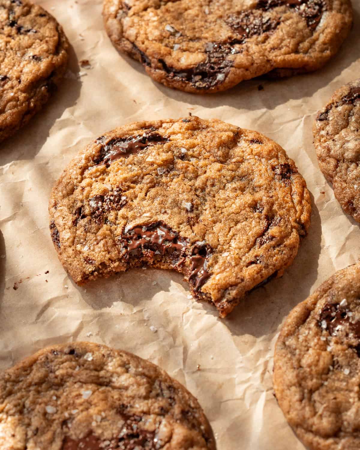 cookies on a parchment paper lined baking sheet, one with a bite taken from it.