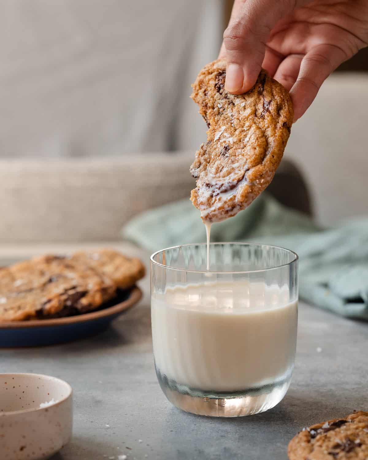 person dipping half a cookie into a glass of milk.