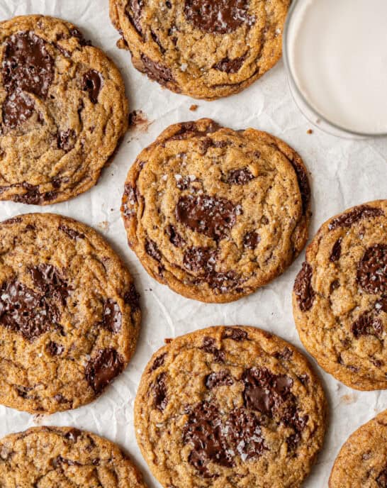 several big vegan chocolate chip cookies on parchment paper.