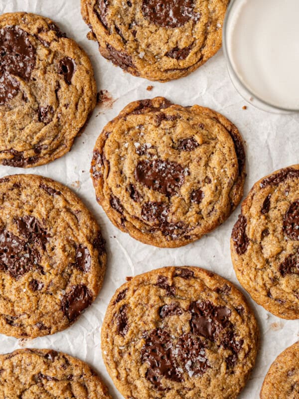 several big vegan chocolate chip cookies on parchment paper.
