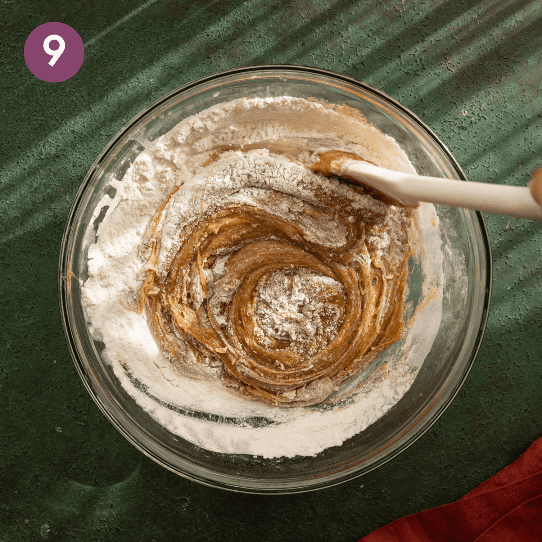 person folding in the dry ingredients with the wet with a silicone spatula.