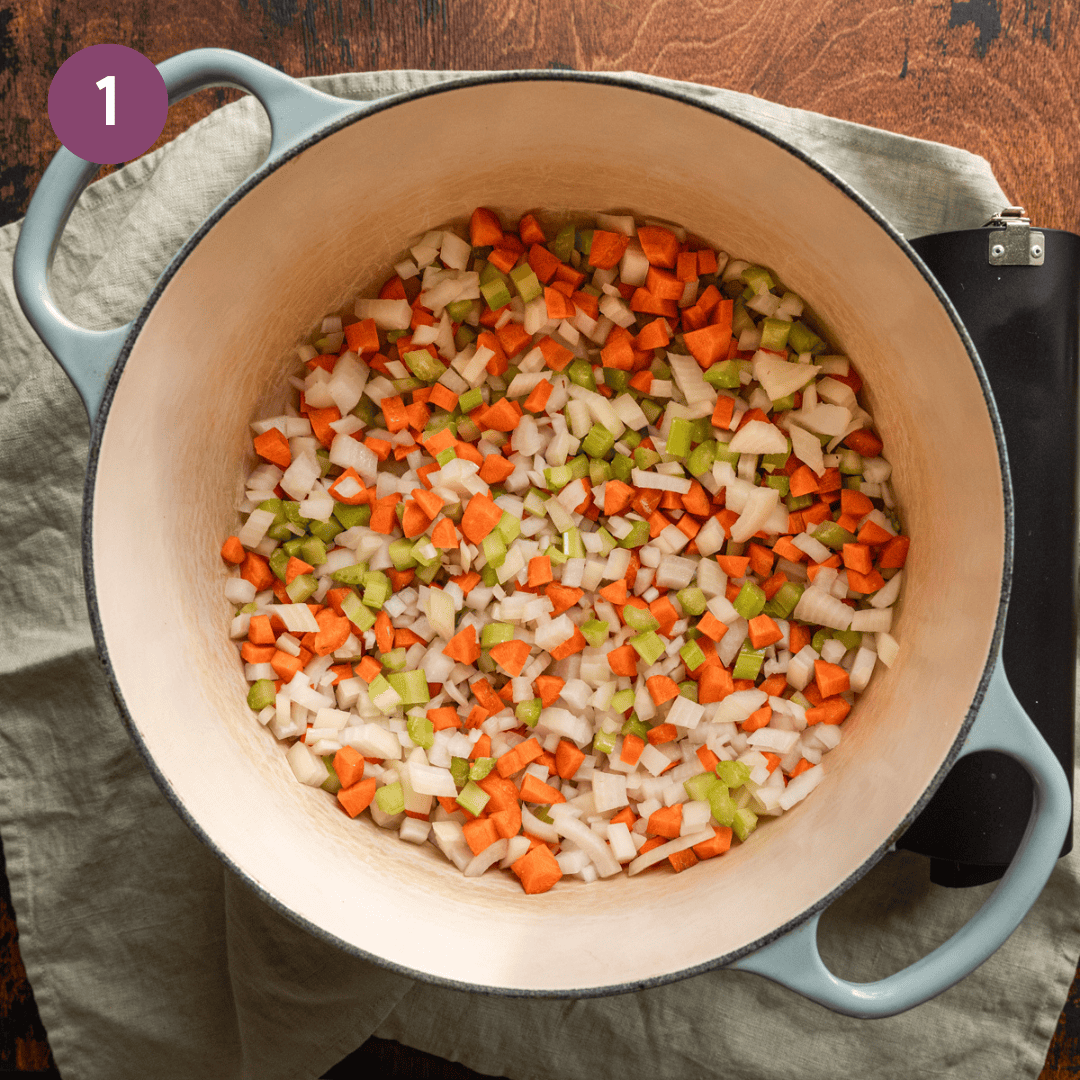 diced onions, carrots, and celery being sauteed in a dutch oven. 