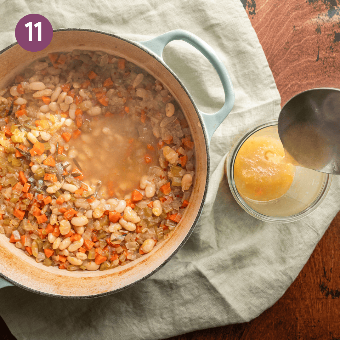 pot of white bean soup, with ladle to the side pouring broth into a glass. 