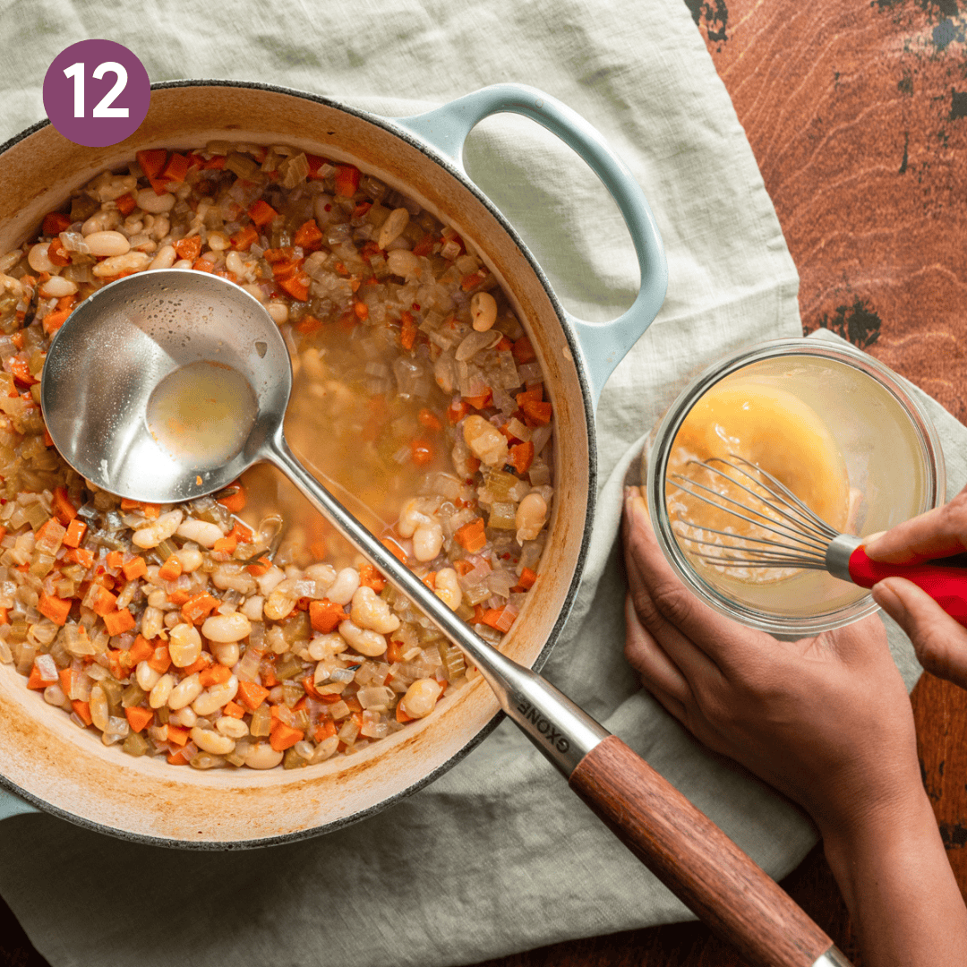 pot of white bean soup, with woman's hands whisking jar of broth.