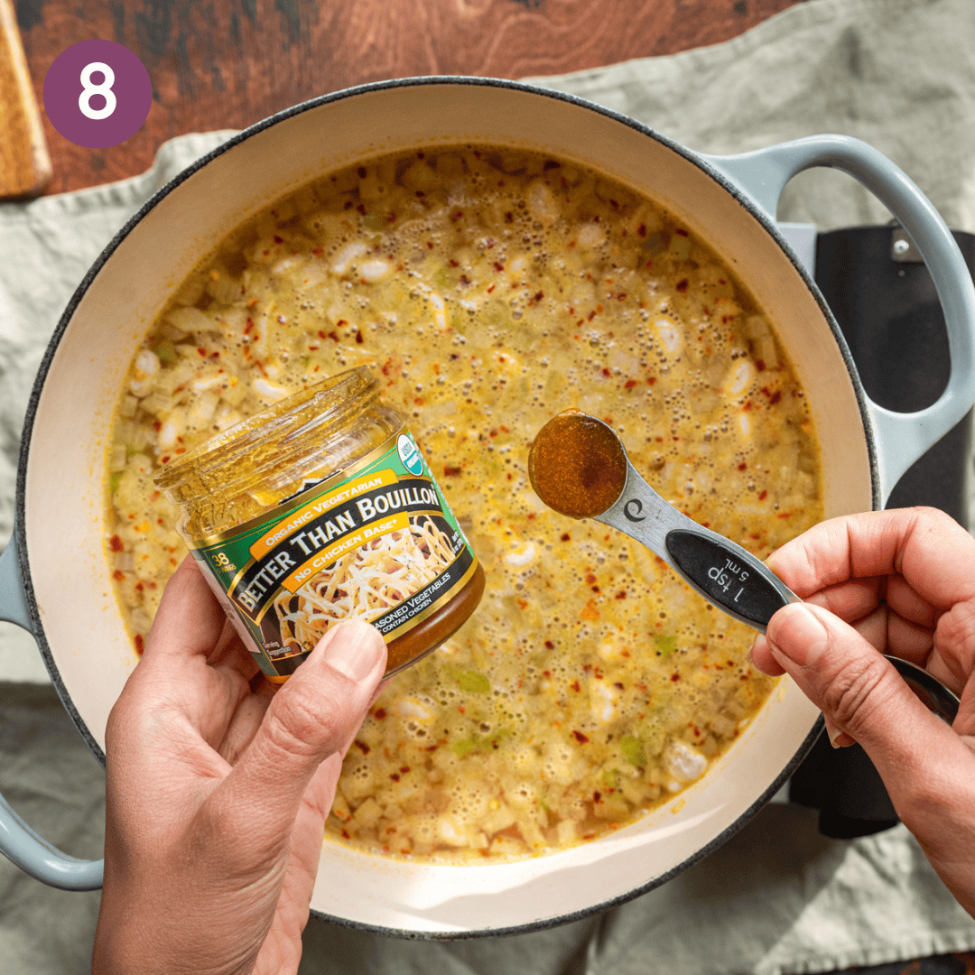 woman's hands holding a jar of Better than Bouillon over a pot of simmering soup. 