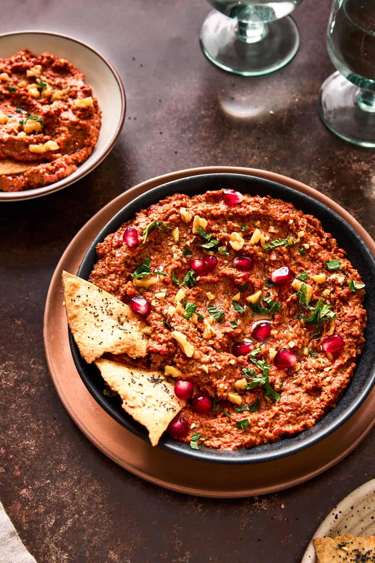 muhammara with herbs, pomegranate seeds and walnuts in a large bowl with pita chips.