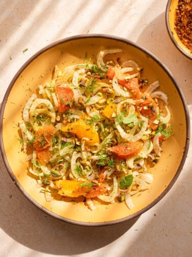 fennel orange salad in a yellow bowl with dappled light.