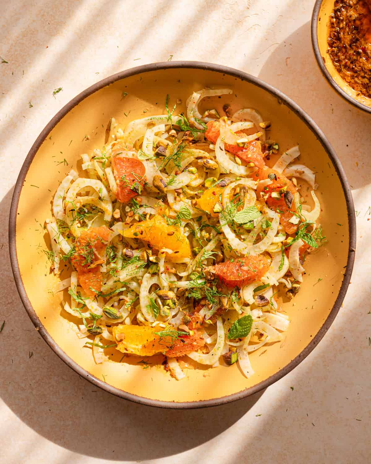 fennel orange salad in a yellow bowl with dappled light.